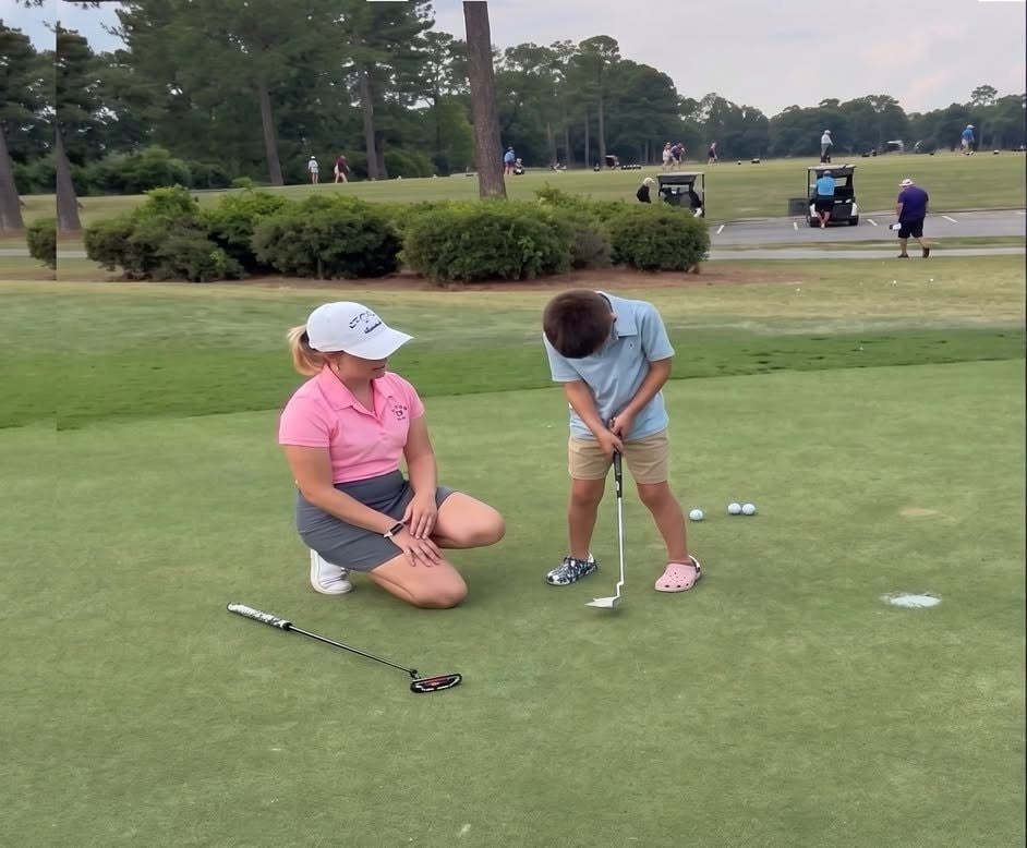 Deb coaching a junior golfer on the putting green