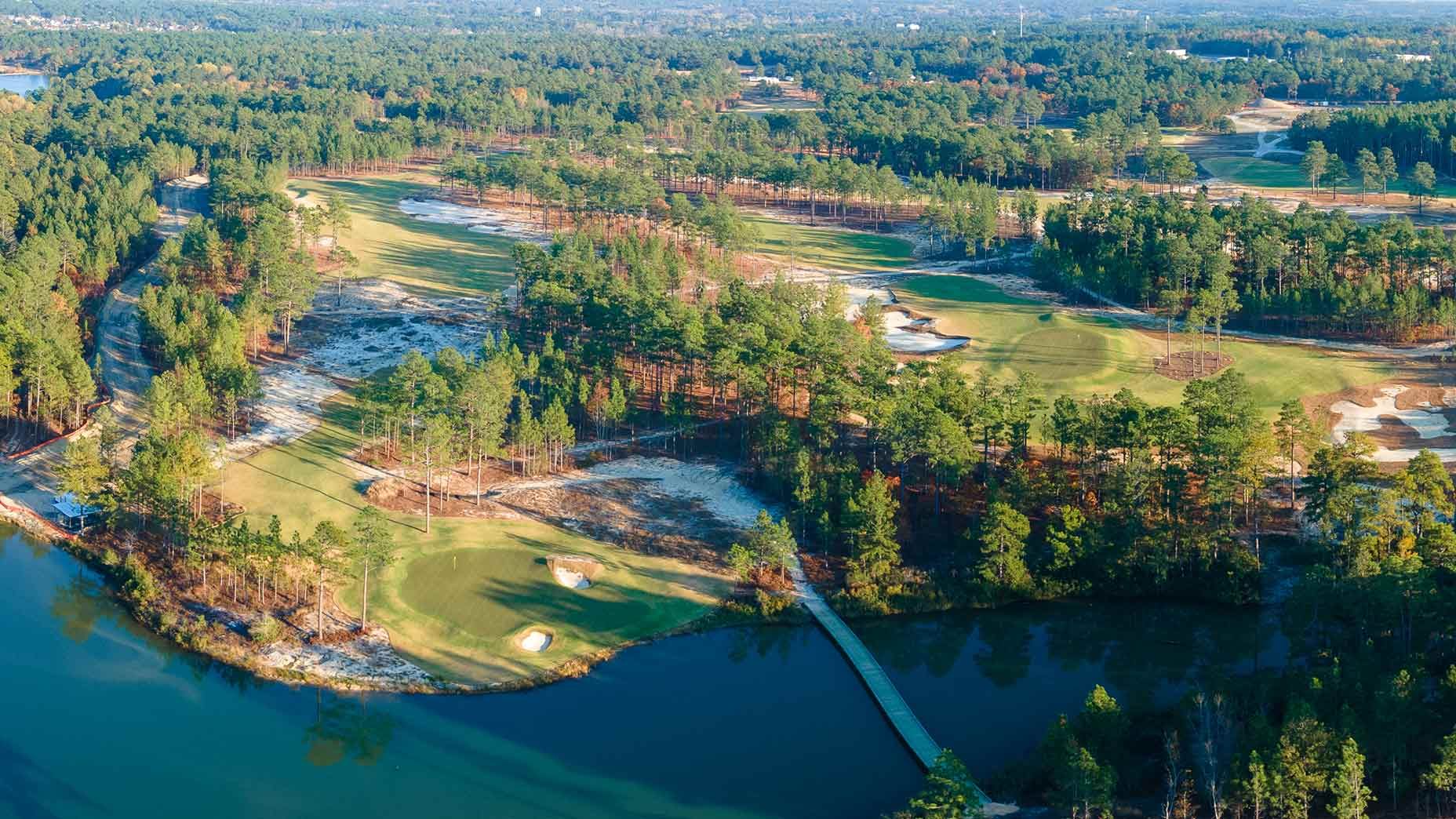 Aerial view of a pine lined golf course beside a lake